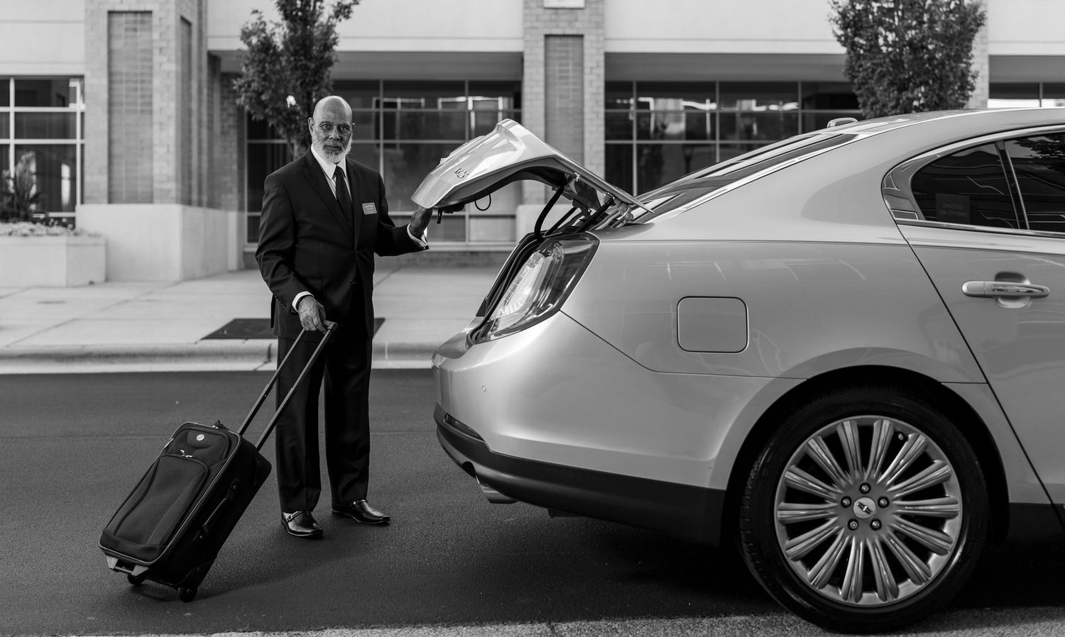 A chauffeur handling a guest's luggage at the kerb